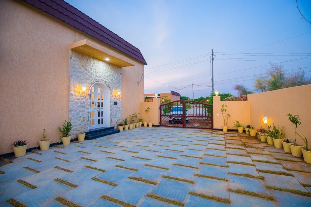 Calista Palms luxury 2BHK villa entrance with spacious paved courtyard and warm evening lighting in Udaipur