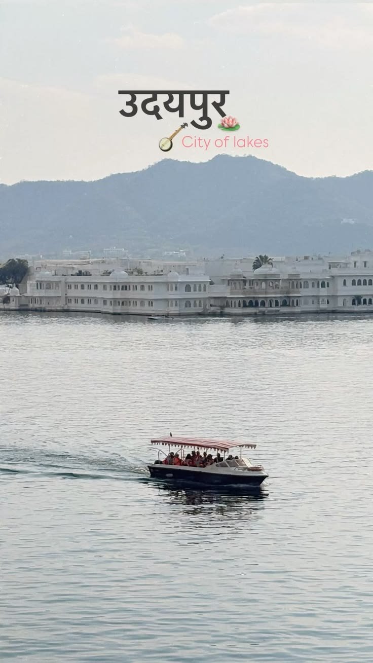 Tourist boat cruising on Lake Pichola with Taj Lake Palace and Aravalli hills in the background