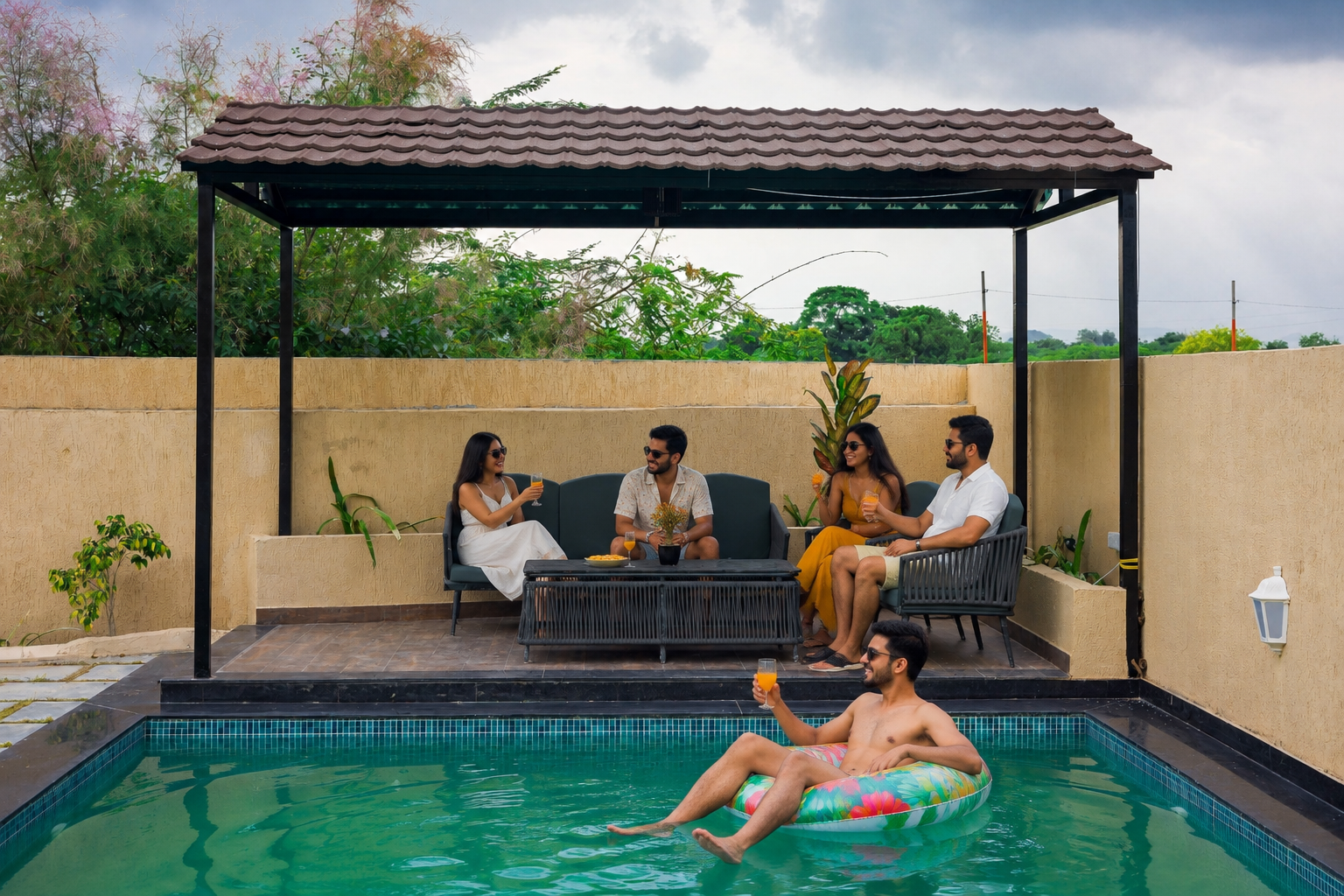 A group of friends enjoying a fun evening at a private luxury villa in Udaipur, relaxing by the swimming pool and garden area with drinks, music and great company. The scene highlights the villa’s private pool, outdoor seating and peaceful getaway atmosphere.