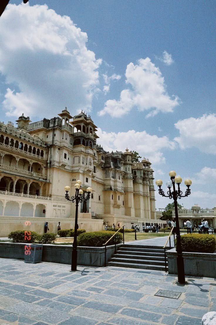 Exterior view of Udaipur City Palace featuring ornate balconies, courtyards, garden walkways, and classic street lamps.
